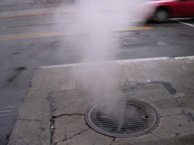 A street grate, pouring out steam