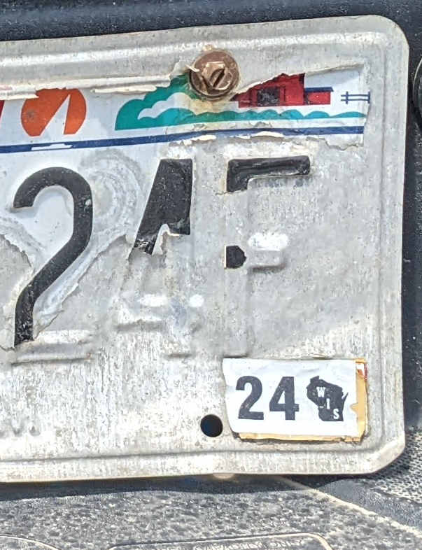 Photograph of part of a license plate with the paint for several digits peeling off