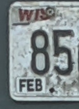 Photograph of part of a license plate with the paint for several digits peeling off