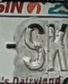 Photograph of part of a license plate with the paint for several digits peeling off