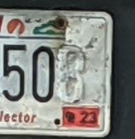 Photograph of part of a license plate with the paint for several digits peeling off